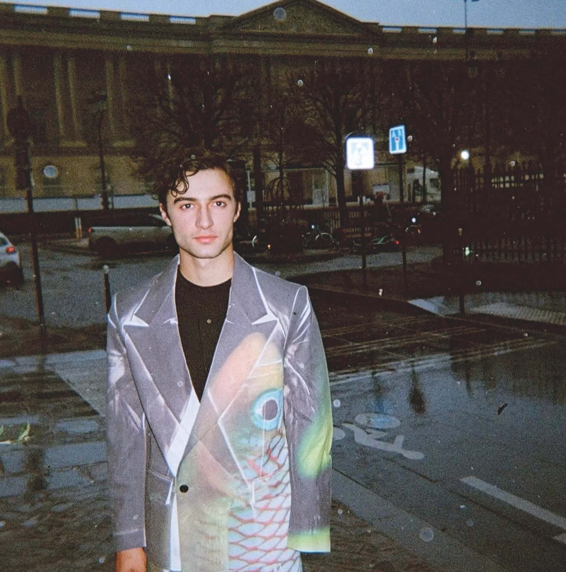 Ezra smiling at the camera dressed in a suit