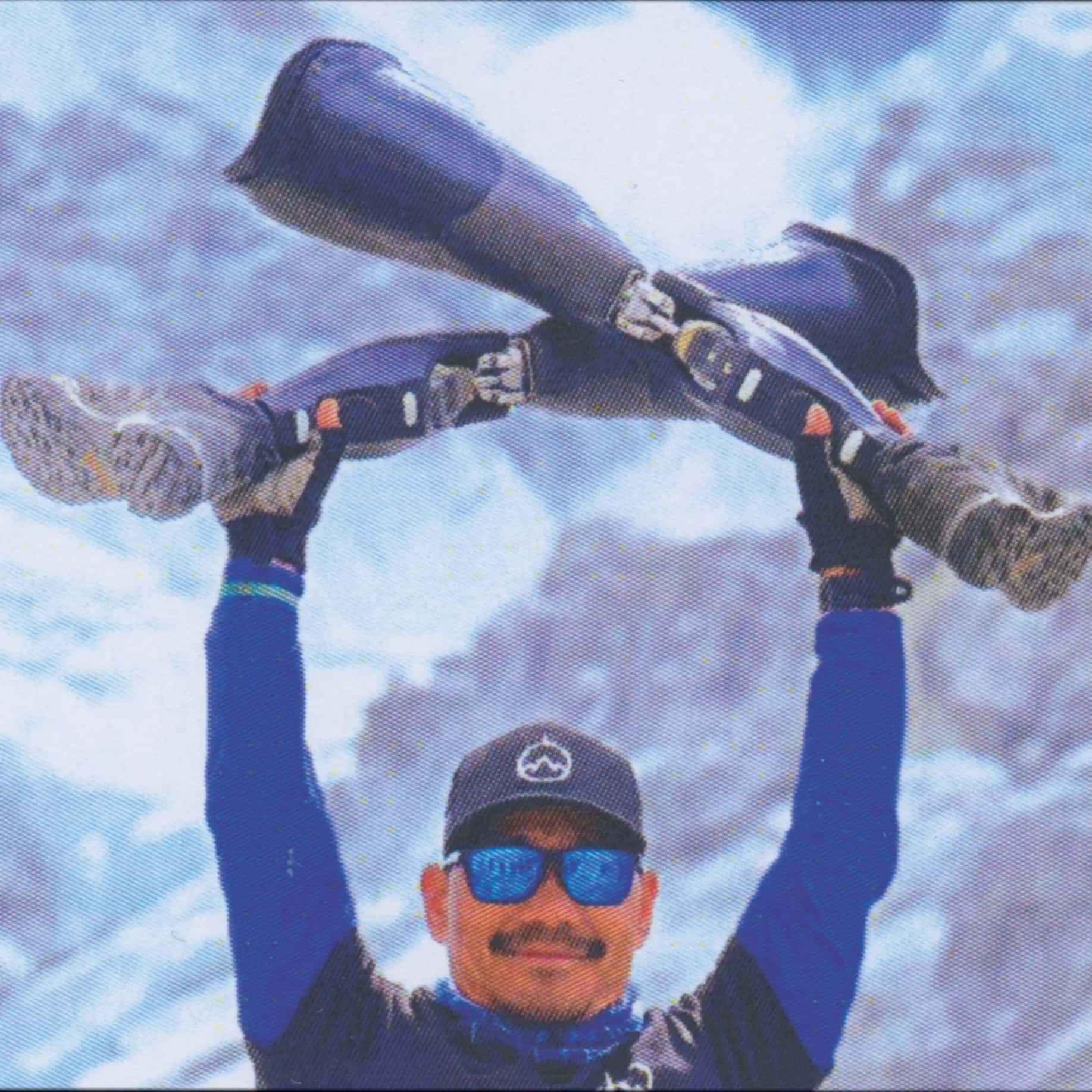 Hari on top of a mountain with prosthetic legs and climbing gear