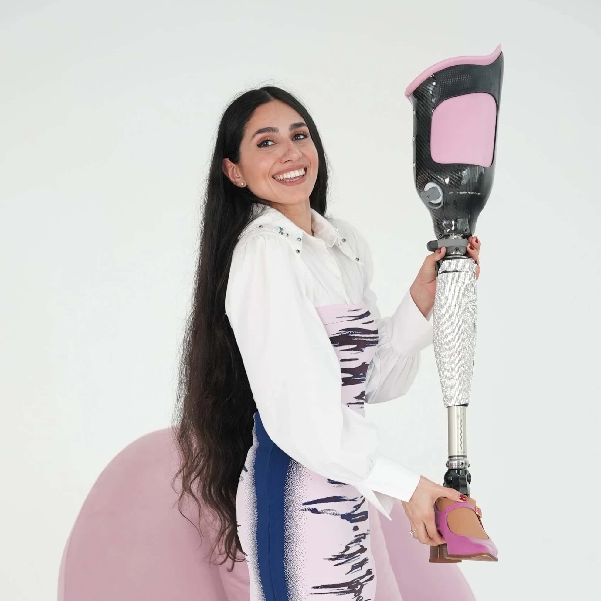 Zainab looking into the camera and smiling and showing her prosthetic leg